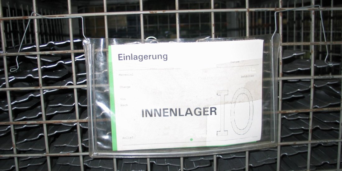Exemple négatif : conteneur grillagé avec étiquette en papier dans une housse de protection