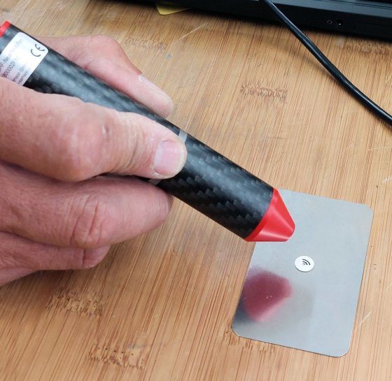 RFID Lesestift liest ein Etikett aus, im Hintergrund ein Laptop